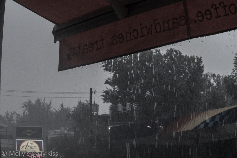 Rain pouring down the awning of a shop