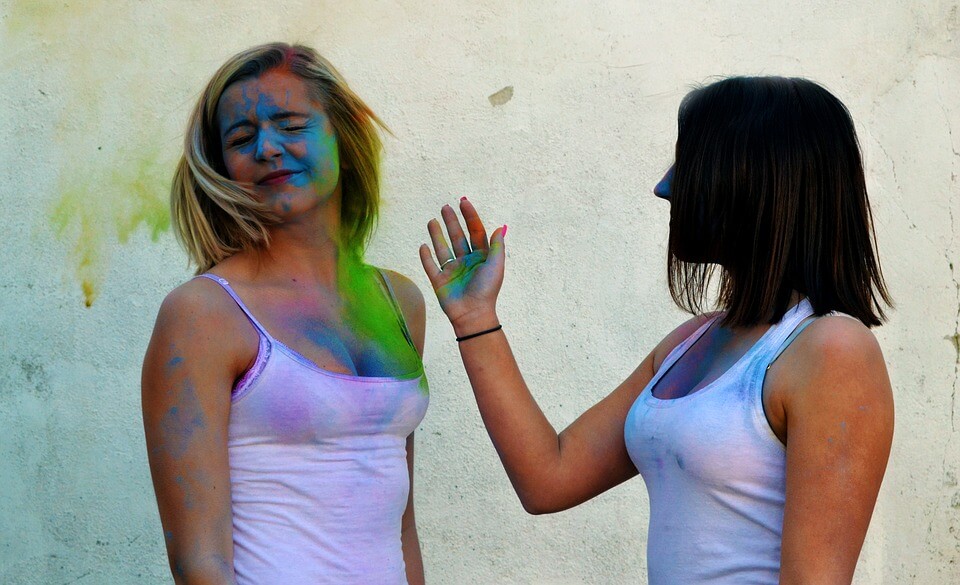 woman slapping other woman's face with coloured powder