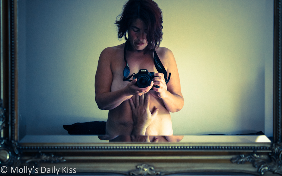 Woman taking topless picture of herself in the mirror for post about erotic photography