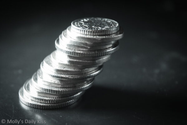 Silver coins stacked up in a leaning tower for post about Financial Domination