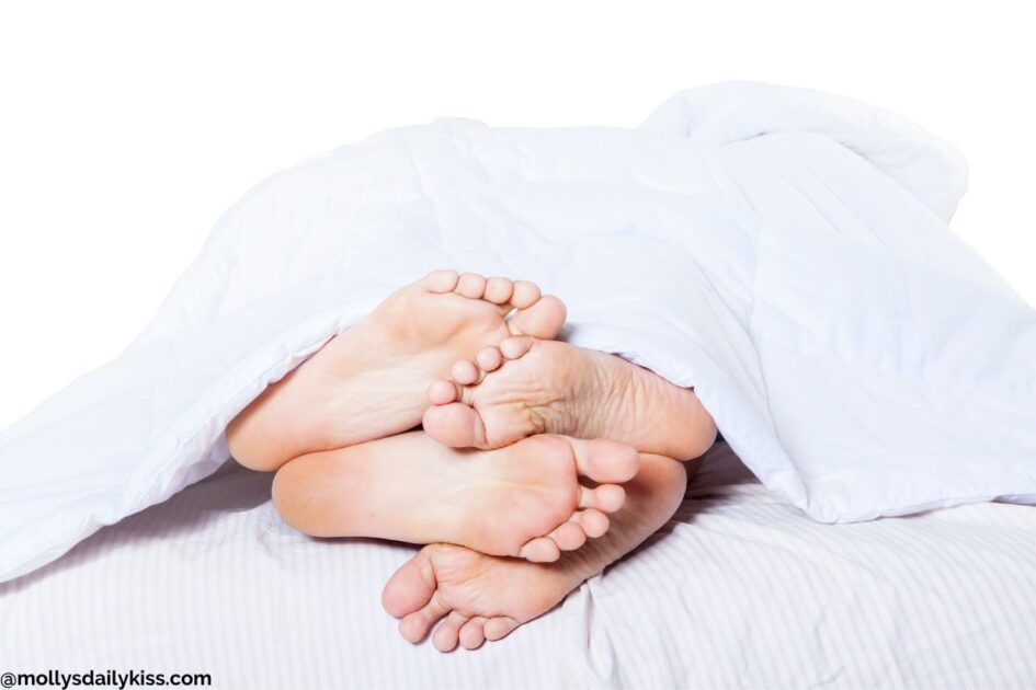 Two set of feet poking out of bed for post about cuddling kink