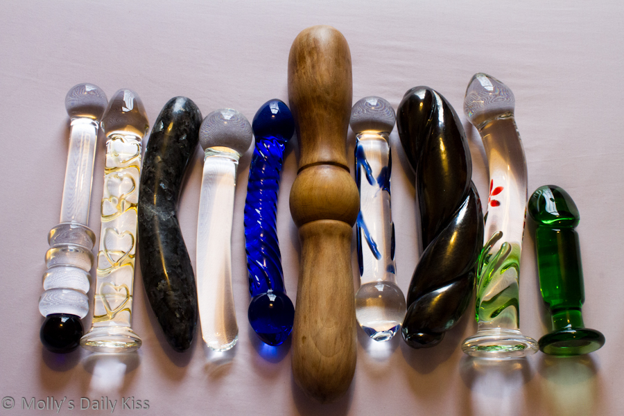 Big selection of dildos lined up on the bed.